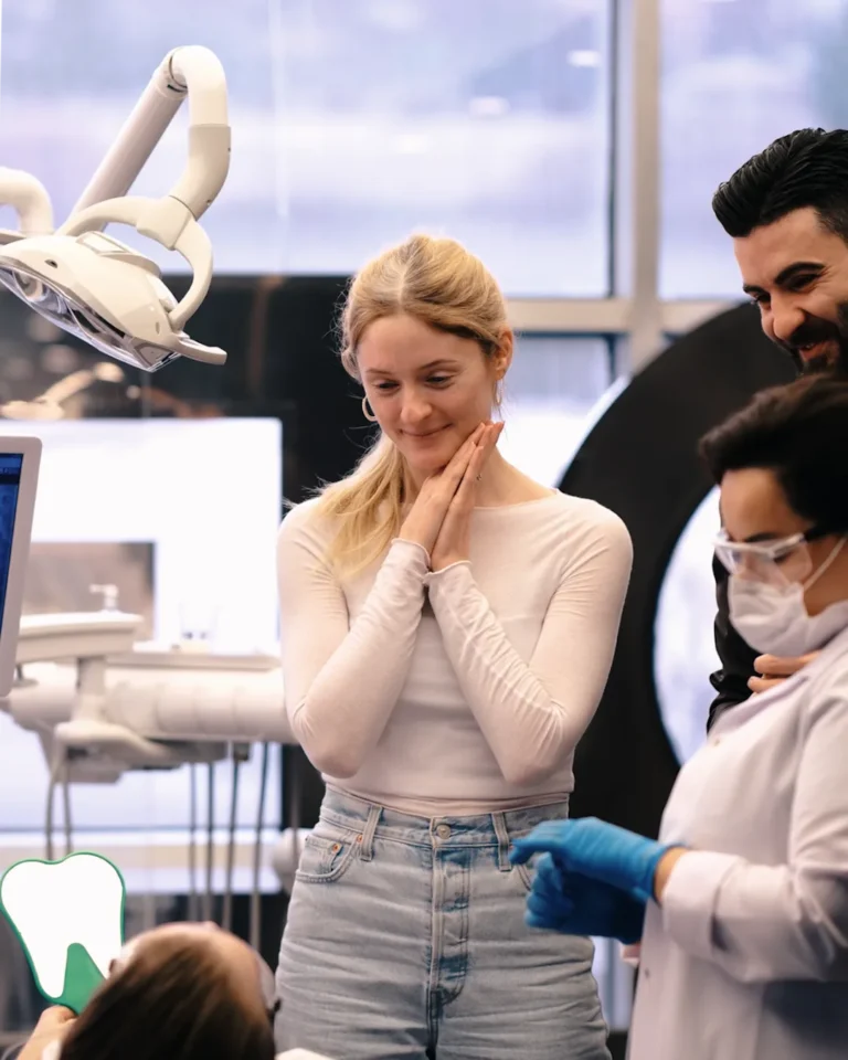 A patient at DentSpa holding her cheeks and smiling beside the dental team