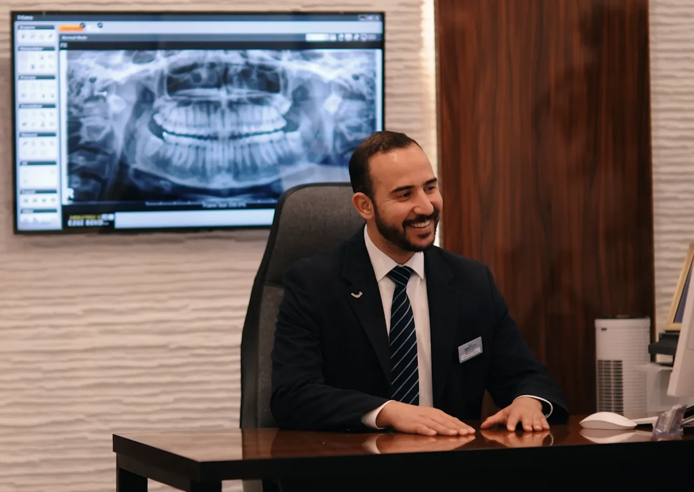 A DentSpa dentist at his desk with a panoramic dental X-ray on the screen behind him